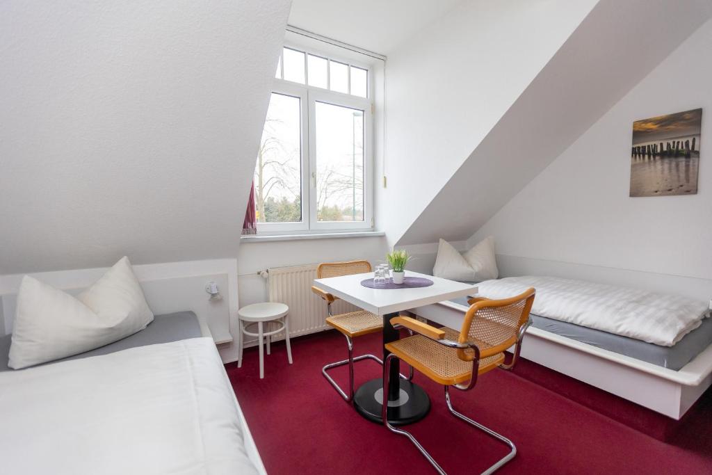 a room with a bed and a table and chairs at Pension Zum Lindeneck in Lübz