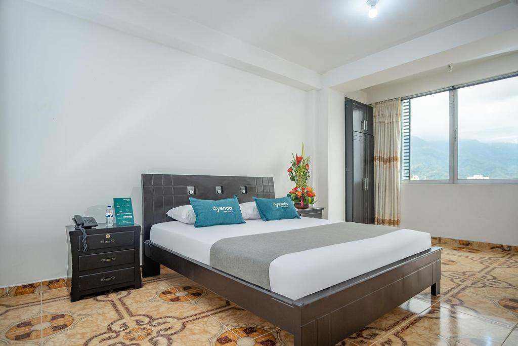 a bedroom with a large bed with blue pillows at Ayenda Gold Plaza in Ibagué