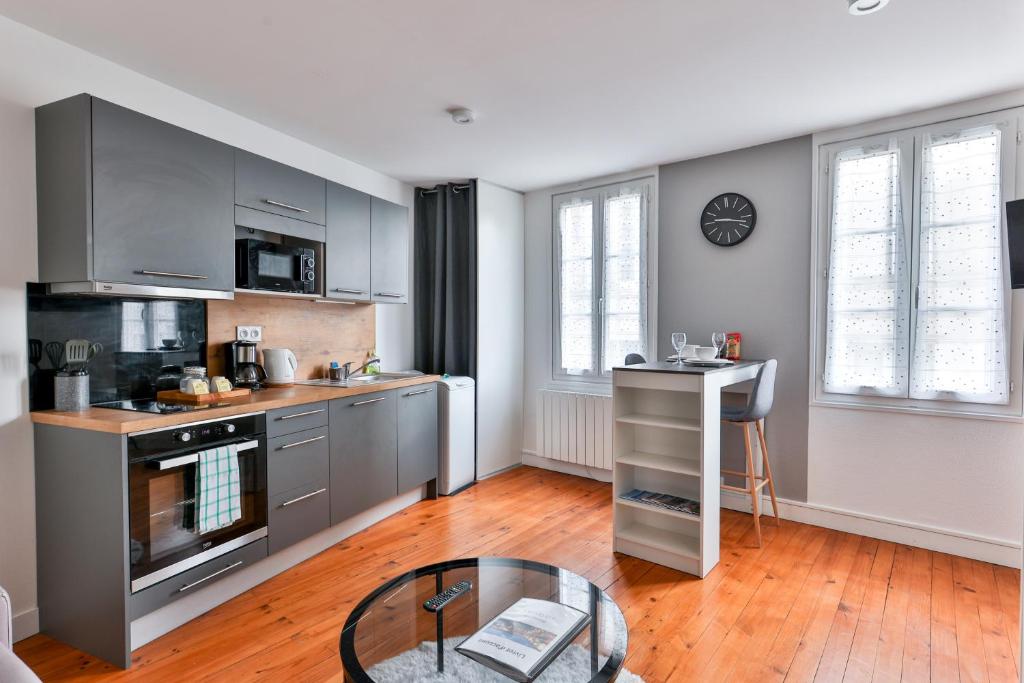 eine Küche mit grauen Schränken und einem Glastisch in der Unterkunft LE COCON #Centre ville #100m de la Charente in Cognac