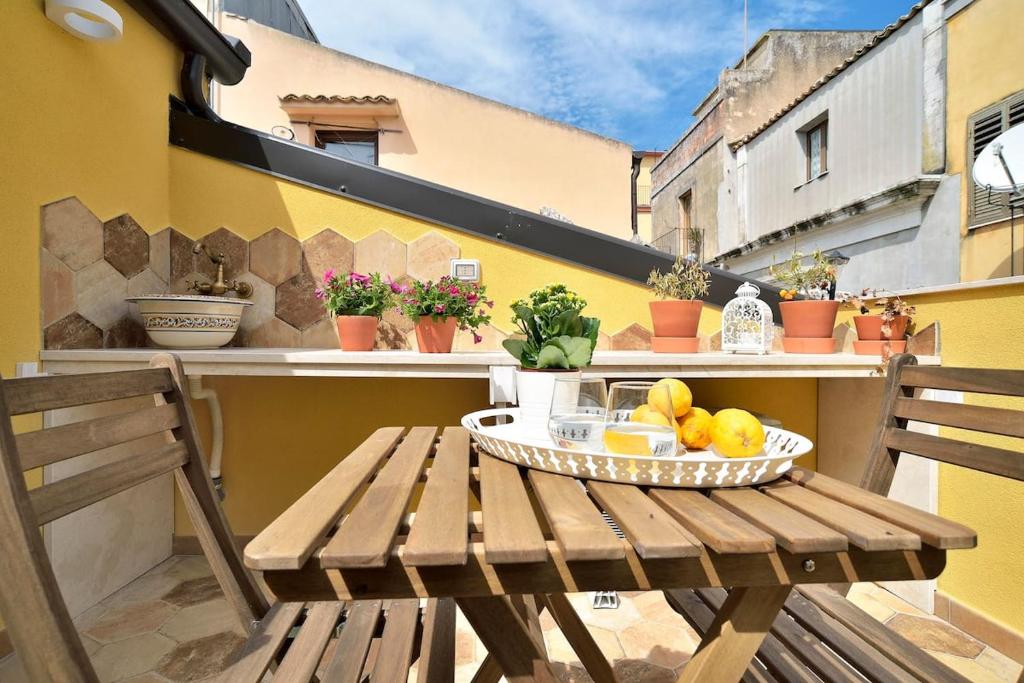 Ragusa exclusive flat with terrace & BBQ في راغوزا: طاولة خشبية مع وعاء من الفواكه على شرفة