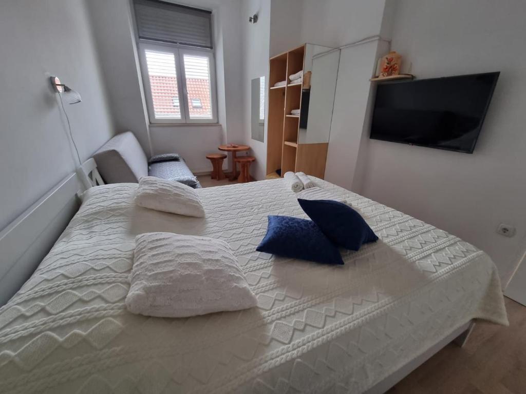 1 dormitorio con 1 cama blanca grande con almohadas azules en Španić palace, en Korčula