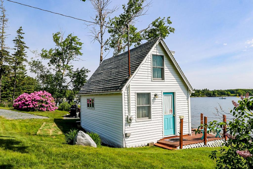 una pequeña casa blanca a orillas de un lago en Dream Harbor Cottage en Surry