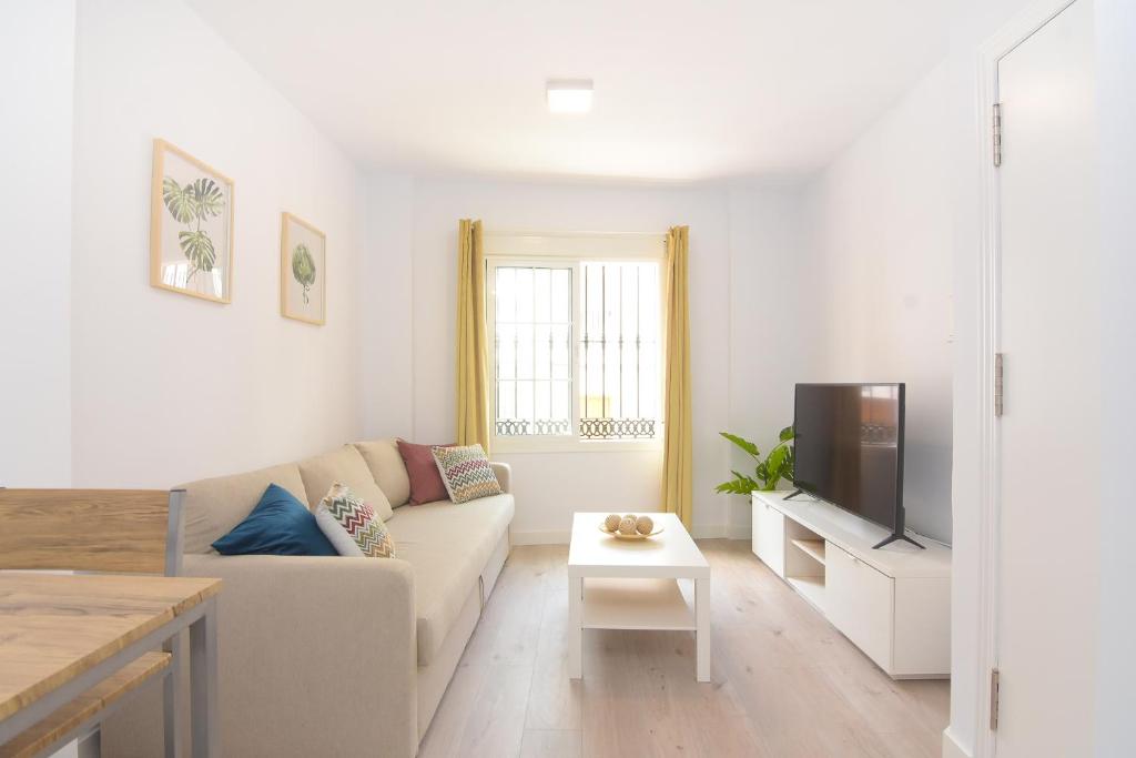 een witte woonkamer met een bank en een tv bij Apartamento recién reformado en el centro de Nerja in Nerja