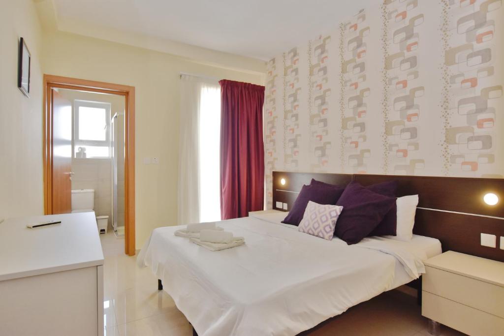 a bedroom with a large white bed with purple pillows at 101 Moroni by Cast Renting in Il-Gżira