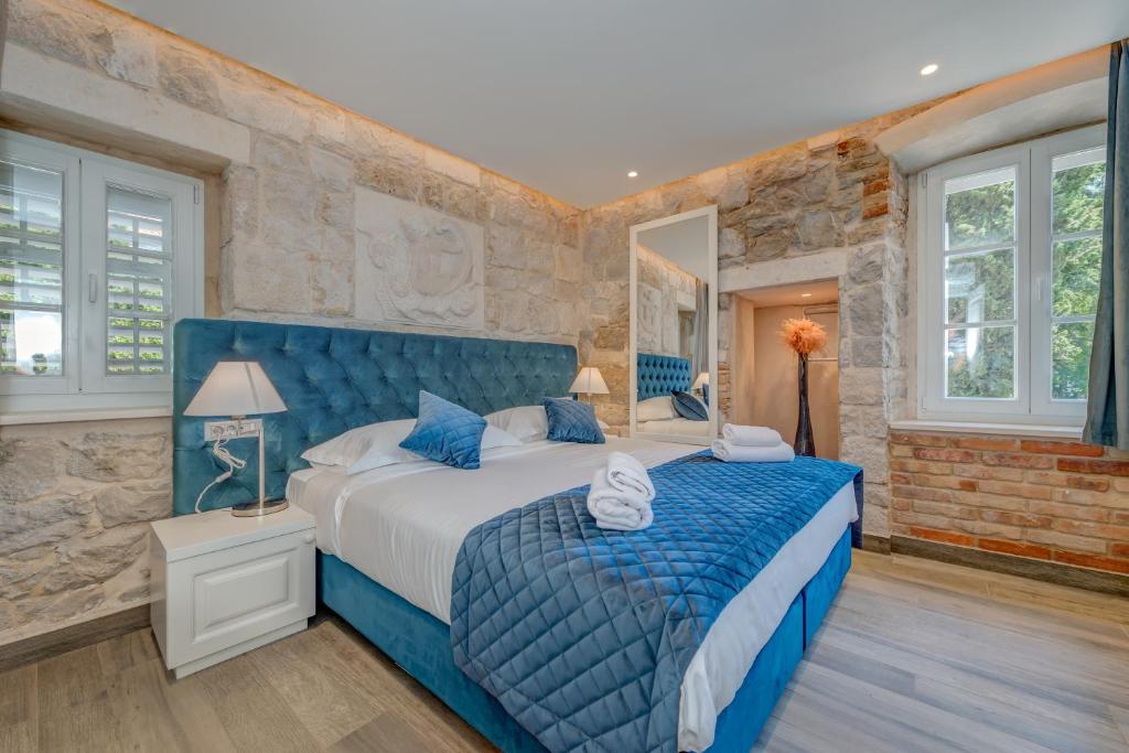 a bedroom with a blue bed and a brick wall at Stonemasons Heritage in Split