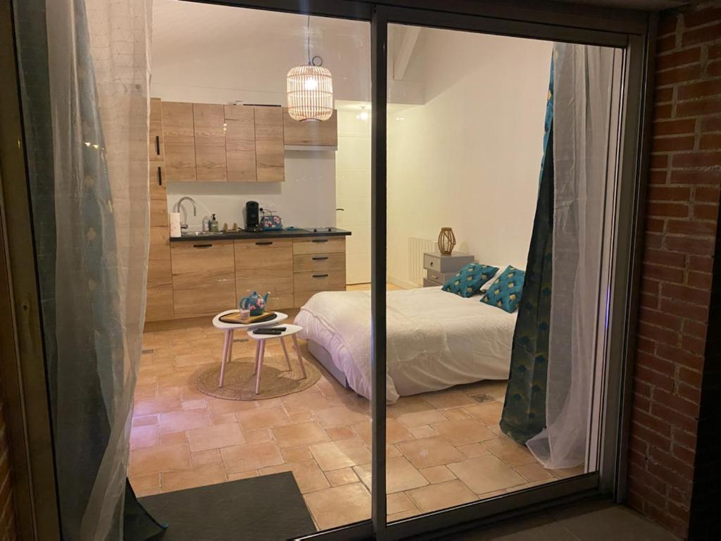Cet appartement comprend une chambre avec un lit et une table ainsi qu'une cuisine. dans l'établissement Hébergements indépendants proches aéroport de Nantes Atlantique et centre ville de Nantes, à Saint-Aignan-Grand-Lieu