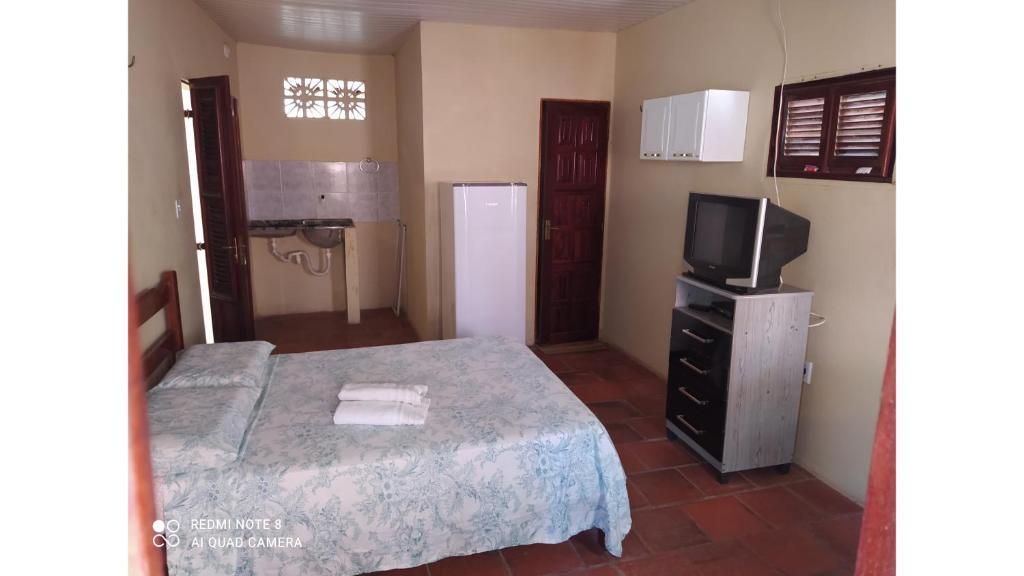 Dormitorio pequeño con cama y TV en Suítes D'Belinha, en Canoa Quebrada