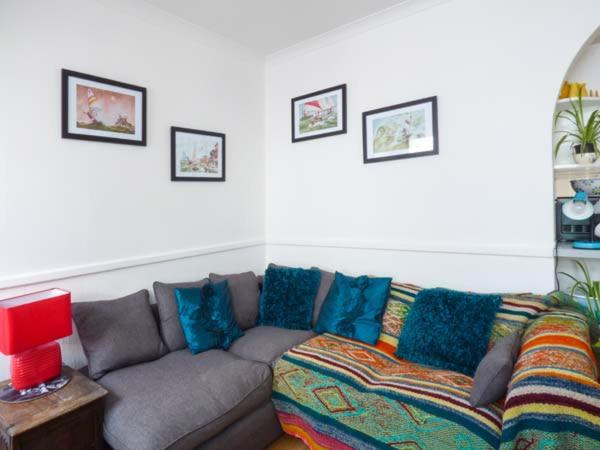 uma sala de estar com um sofá cinzento com almofadas azuis em Tidewood em Polzeath