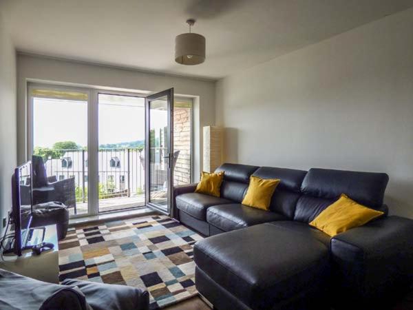 a living room with a black leather couch and yellow pillows at Tehidy in Charlestown