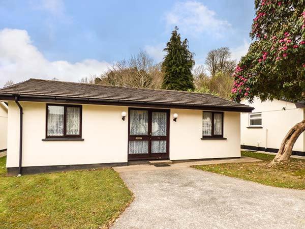 ein weißes Haus mit schwarzen Fenstern und einer Auffahrt in der Unterkunft Chy Lowenna in Saint Cleer