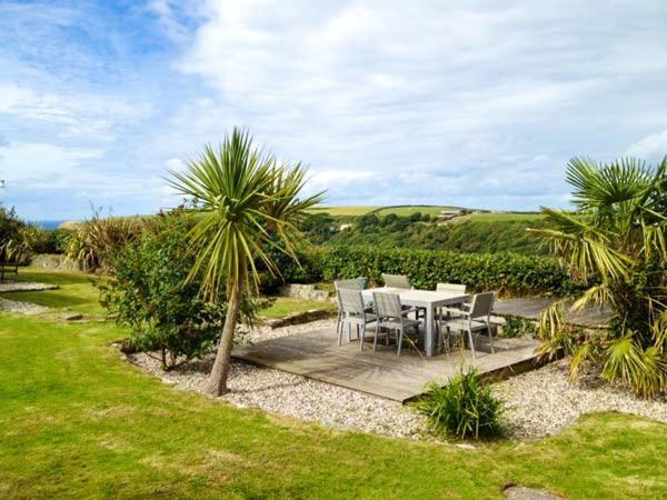 a table and chairs in a garden with palm trees at Nans-Tek in Crackington Haven