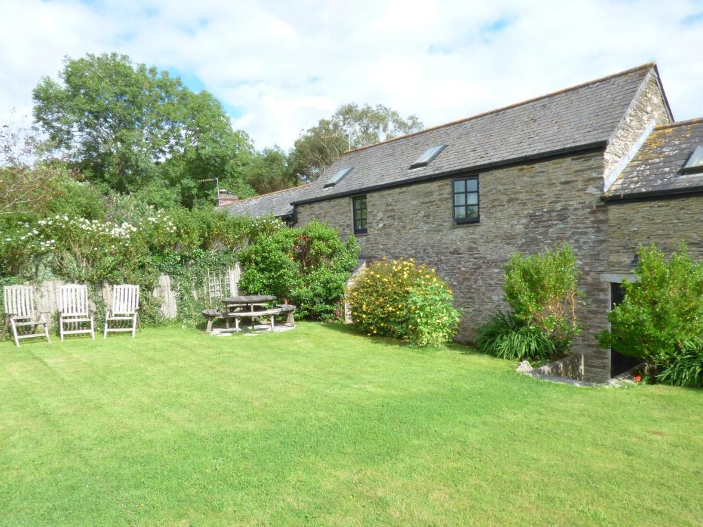 a house with a yard with chairs and a table at Meadow Cottage in Fowey
