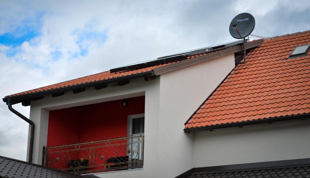 a white building with a red roof and a balcony at Guesthouse Pink Panther in Udbina