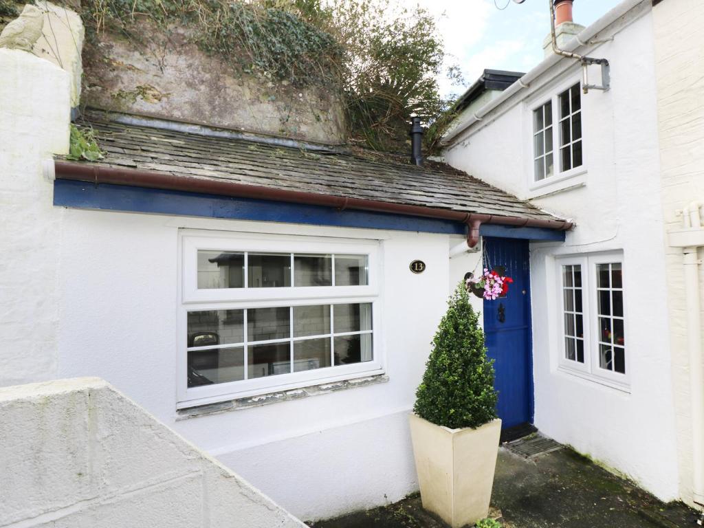a white house with a blue door and a christmas tree at 13 Castle Hill in Lostwithiel