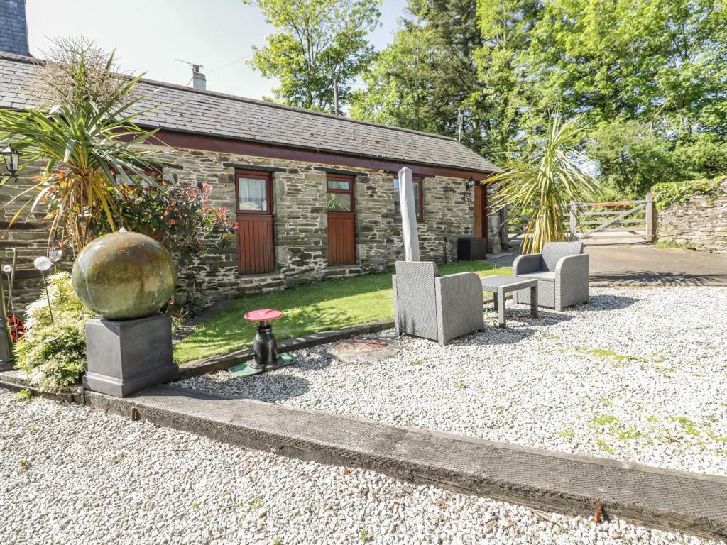 a stone cottage with two chairs and a table at Cosy Cottage in Liskeard