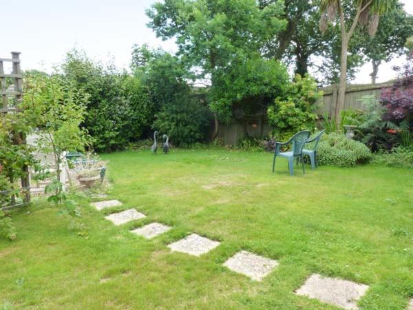 a yard with two benches and a dog in the yard at Joylands in Budock Water