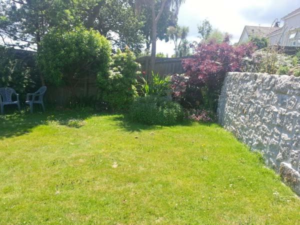 a backyard with a stone wall and a yard with a lawn sidx sidx at Joylands in Budock Water