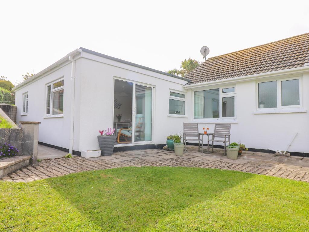 une maison blanche avec un patio et une cour dans l'établissement Bre An Mor, à Germoe