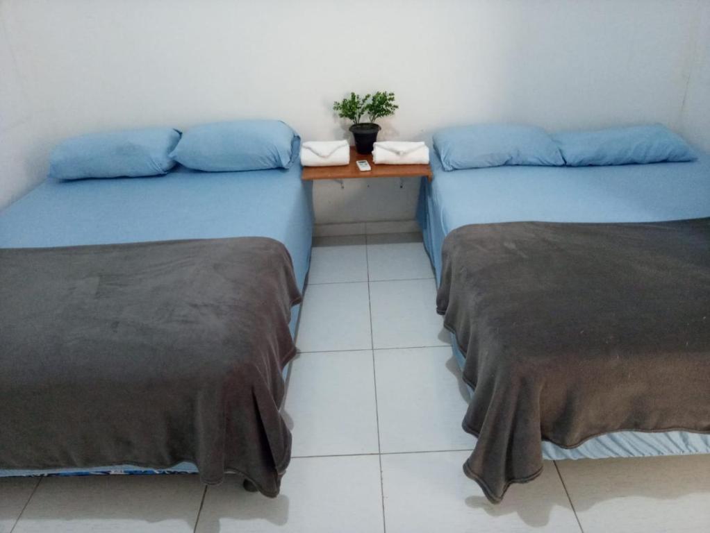 twee bedden in een kamer met een tafel ertussen bij Casa Piauí Hostel in Teresina