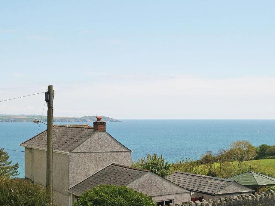 a house on a hill with the ocean in the background at Driftwood Cottage in St Austell
