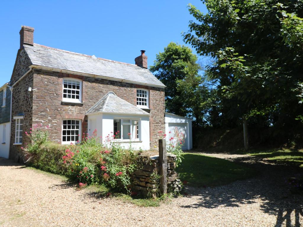 an old brick house with flowers in front of it at Trenouth Cottage in Padstow