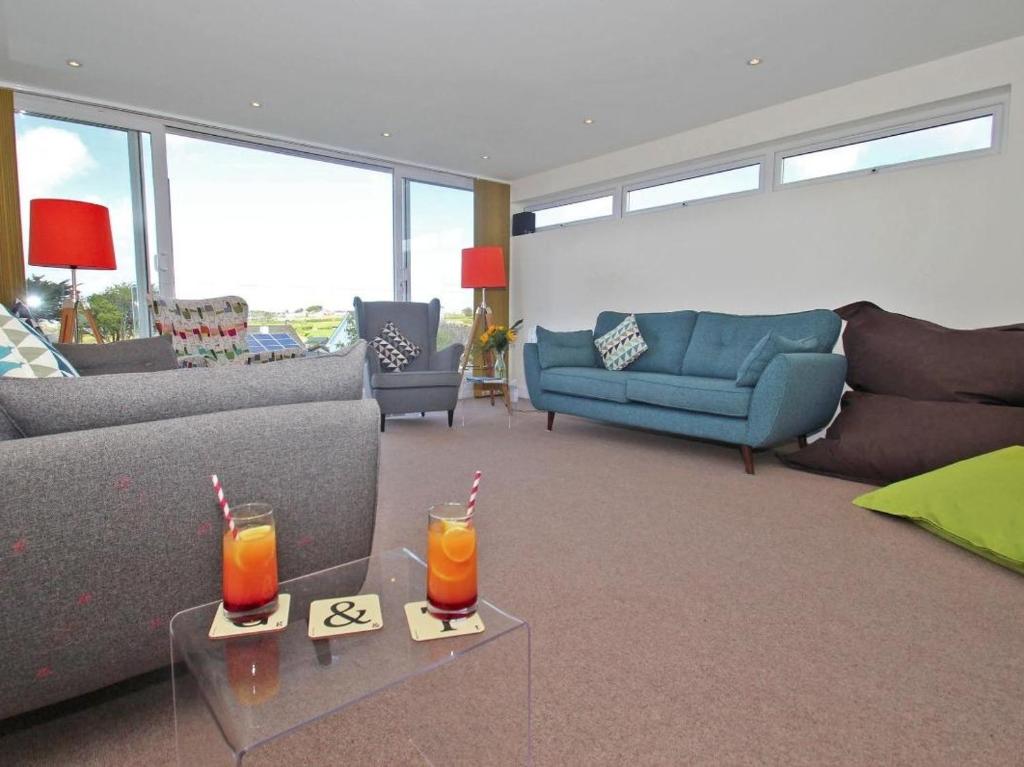 a living room with a couch and two drinks on tables at Seagrass in Newquay