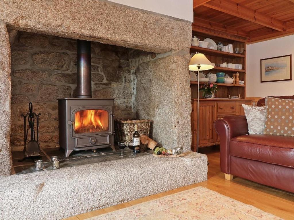 a living room with a stone fireplace and a couch at Halvosso in Penryn