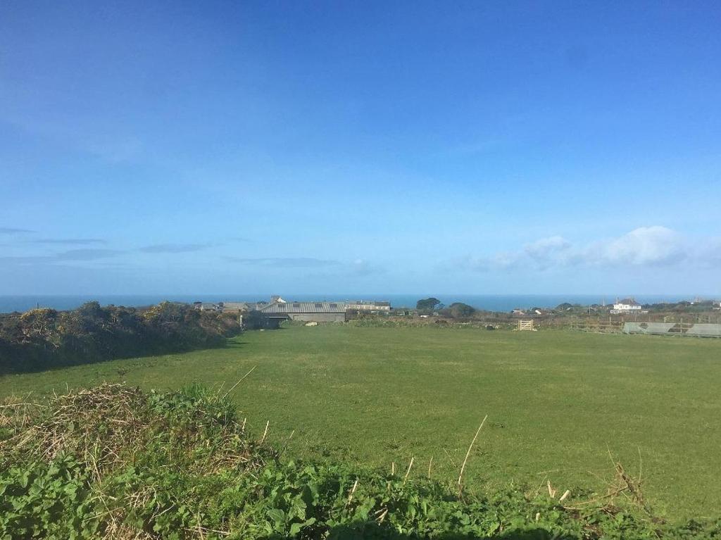 a large green field with the ocean in the background at Five Degrees West in St. Just