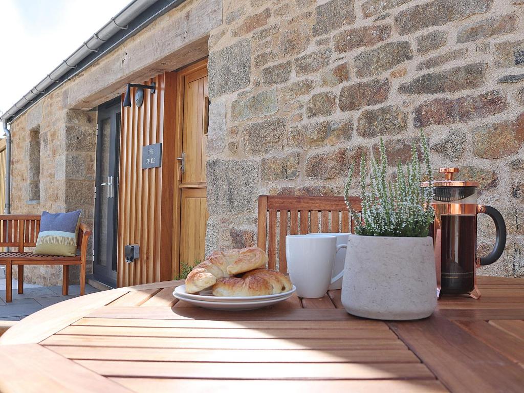 Una mesa con un plato de pan y una taza de café. en The Stable, Boskensoe Barns, en Falmouth