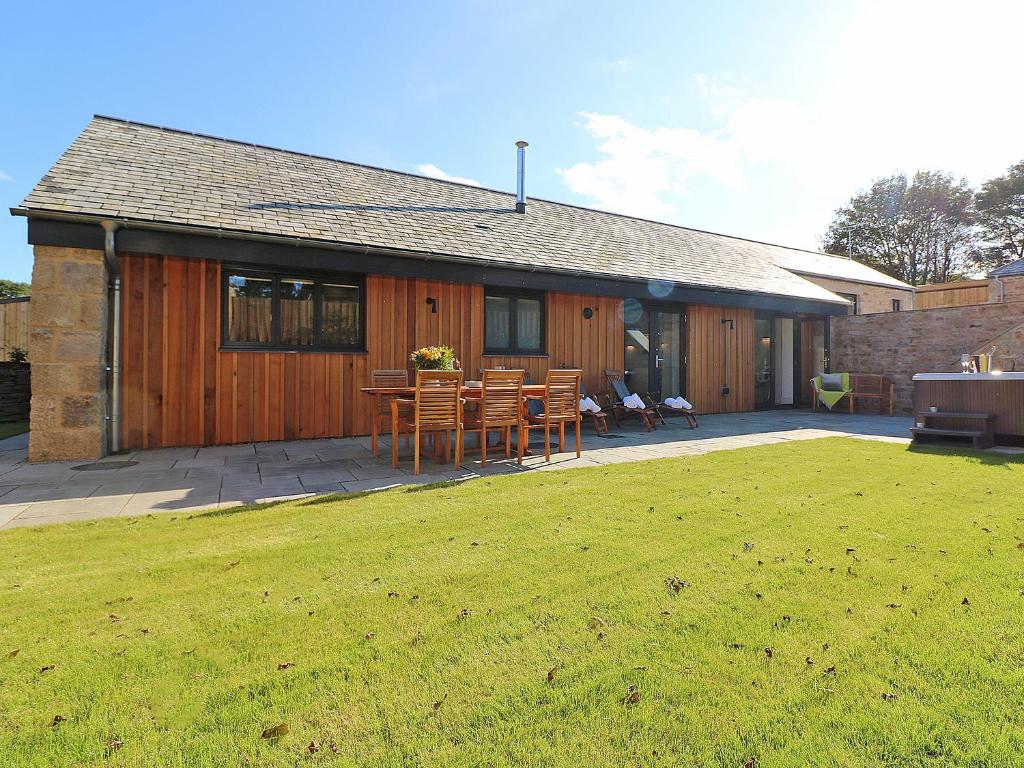 a house with a patio with a table and chairs at Pig House, Boskensoe Barns in Helford Passage