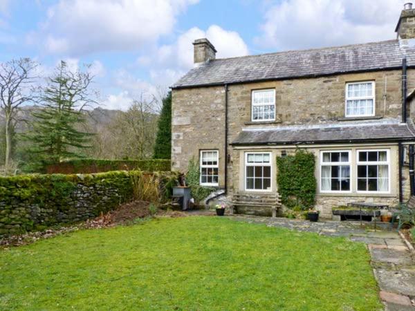 an old stone house with a large yard at Locks Cottage in Langcliffe