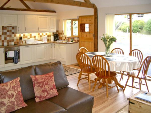 sala de estar con sofá, mesa y cocina en Happy Union Stables, en Abbey-Cwmhir