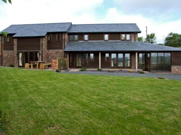 a large wooden house with a large yard at Bushmills in Bacton