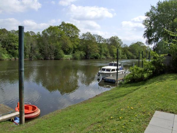 a boat is docked on a river next to a yard at Rosewaters Cottage in Shrawley