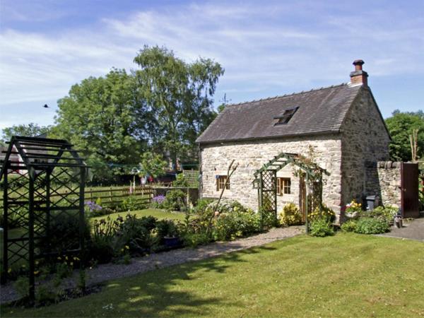 a stone building with a garden in front of it at Church Barn in Tissington