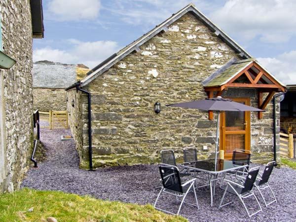 a table and chairs with an umbrella in front of a building at Ty Isaf Penrhyddion in Betws-y-coed