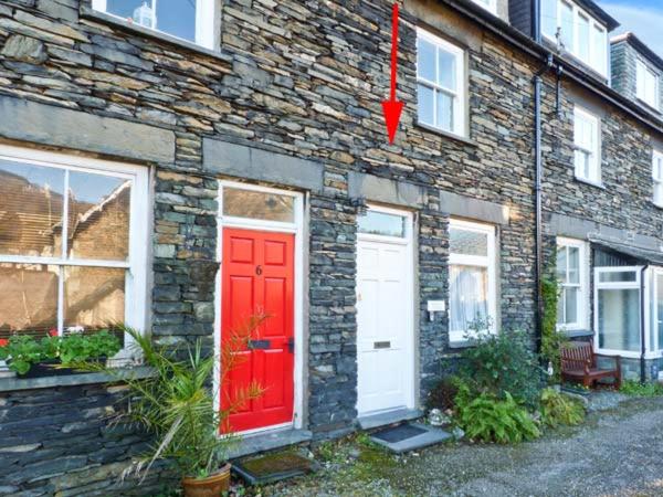 a brick house with a red door and a stone wall at Rothay Cottage in Ambleside