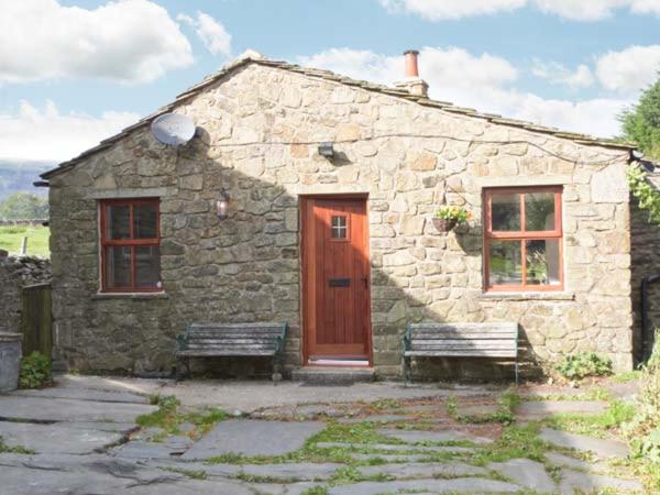 a stone house with a red door and two benches at Wagon House in Horton in Ribblesdale