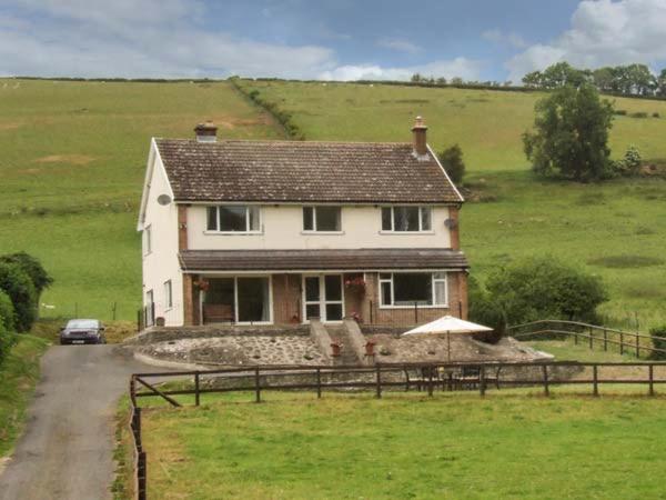 ein großes weißes Haus inmitten eines Feldes in der Unterkunft Cwmgilla Farm in Knighton