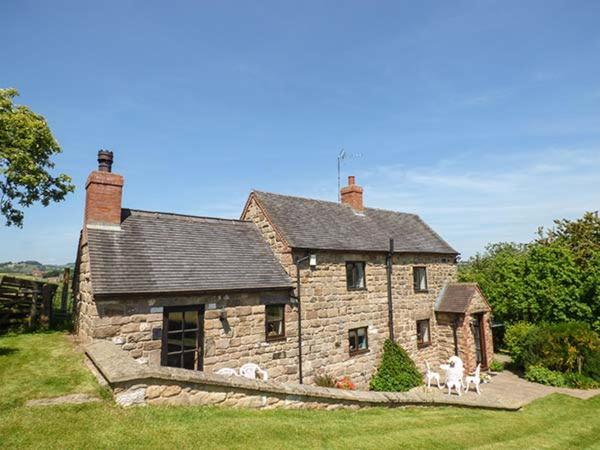 a stone house with three dogs in front of it at Chevinside Cottage in Hazelwood
