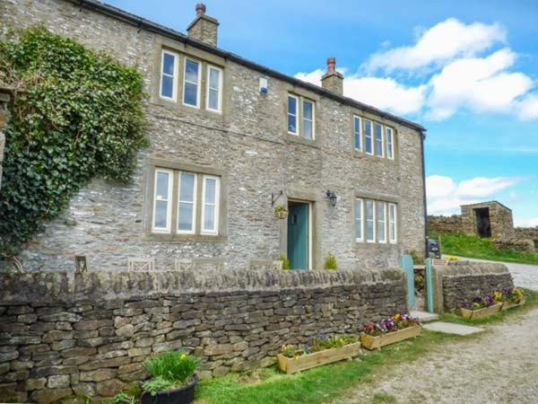 a stone house with a stone wall and a building at Street Head Farm in Cononley