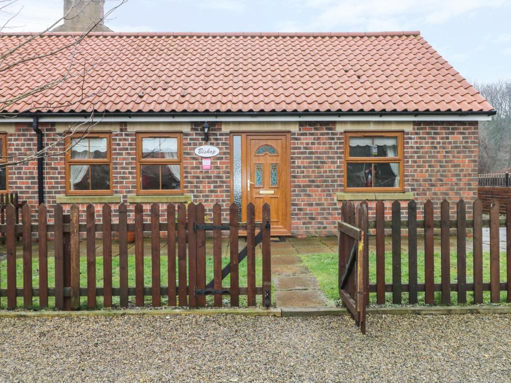 a house with a wooden gate in front of it at Bishop Cottage in Loftus