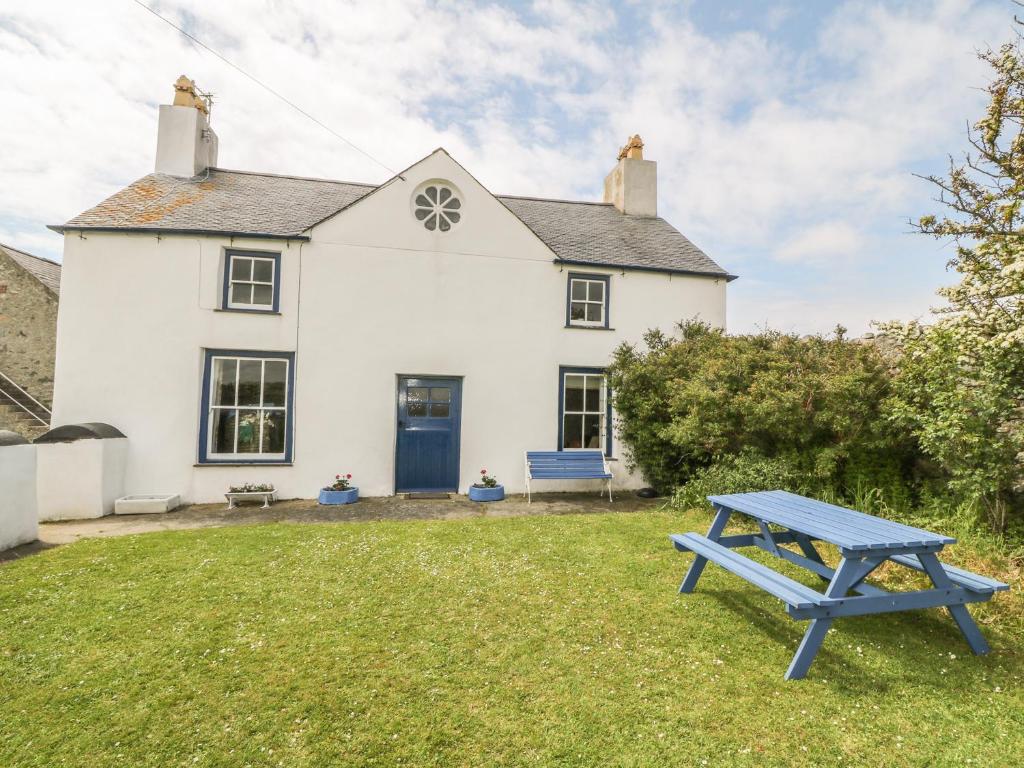 a blue picnic table in front of a white house at Ty Fferm Bodlasan in Llanfachraeth