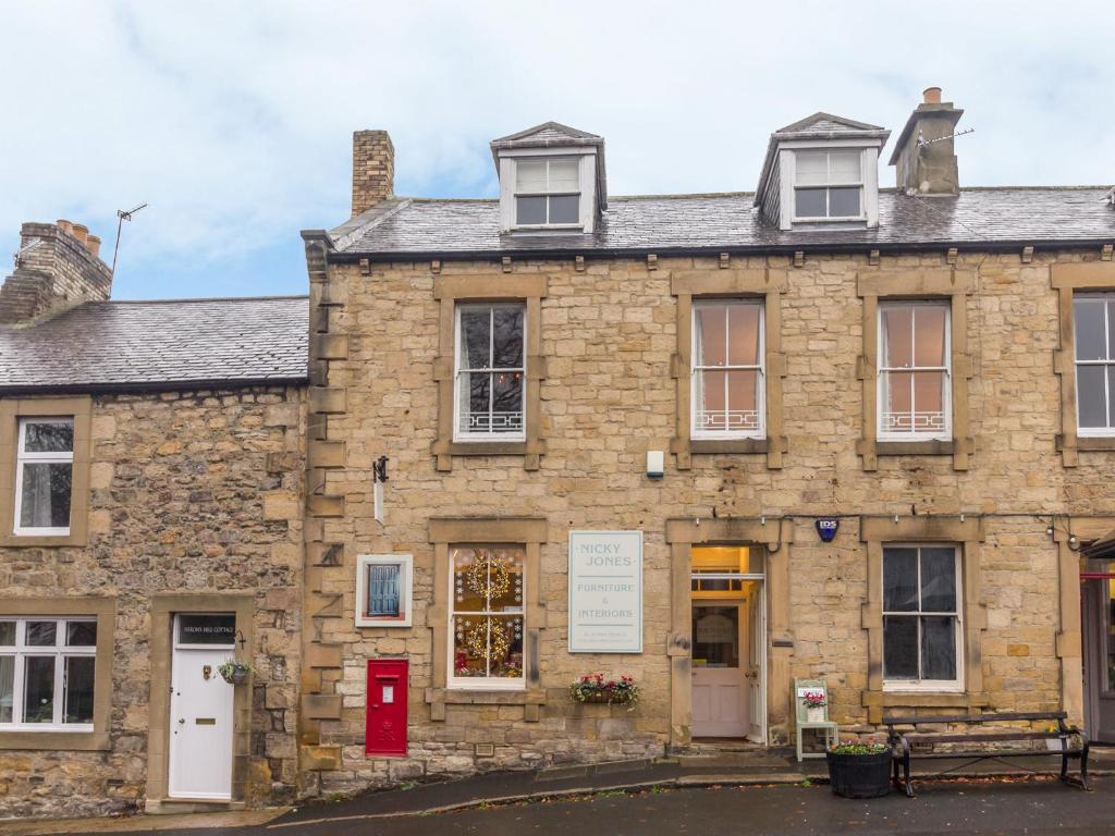 un antiguo edificio de piedra con una puerta roja y ventanas en The Old Exchange, en Corbridge