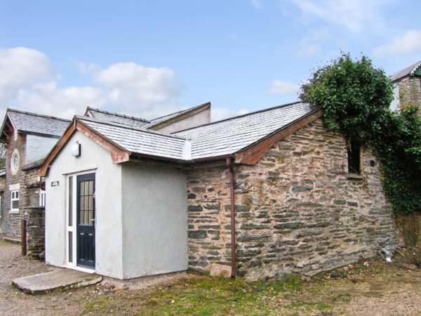uma casa de tijolos com uma porta branca e uma árvore em Hendre Aled Cottage 1 em Llansannan