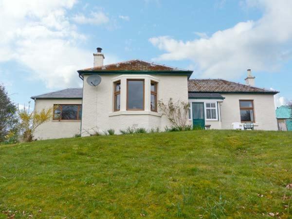a white house on top of a grassy hill at Laxdale Cottage in Banavie