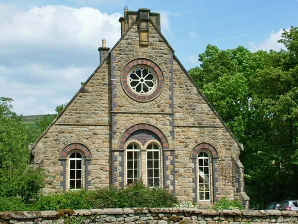 ein Steingebäude mit einem Uhrturm darauf in der Unterkunft 1 The Old Methodist Chapel in Rosedale Abbey