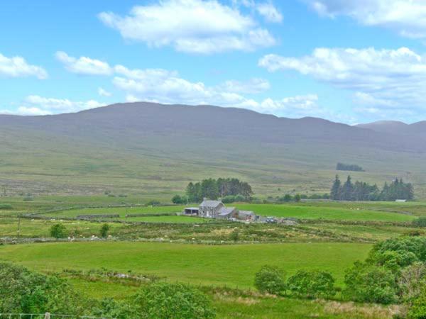 a large green field with a house and mountains in the background at Bryn Re in Trawsfynydd