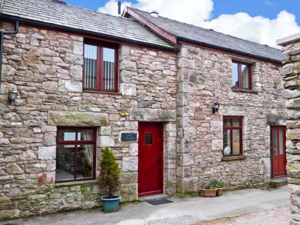 una vieja casa de piedra con una puerta roja y una puerta roja en The Crook en Great Urswick