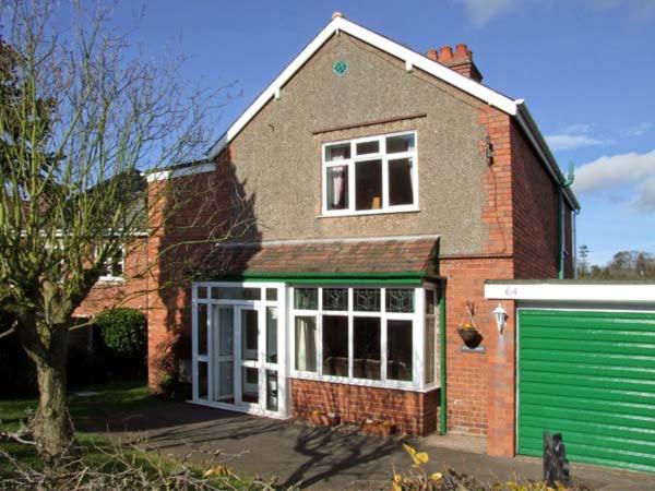 a red brick house with a green garage at Loningside in Wombourn